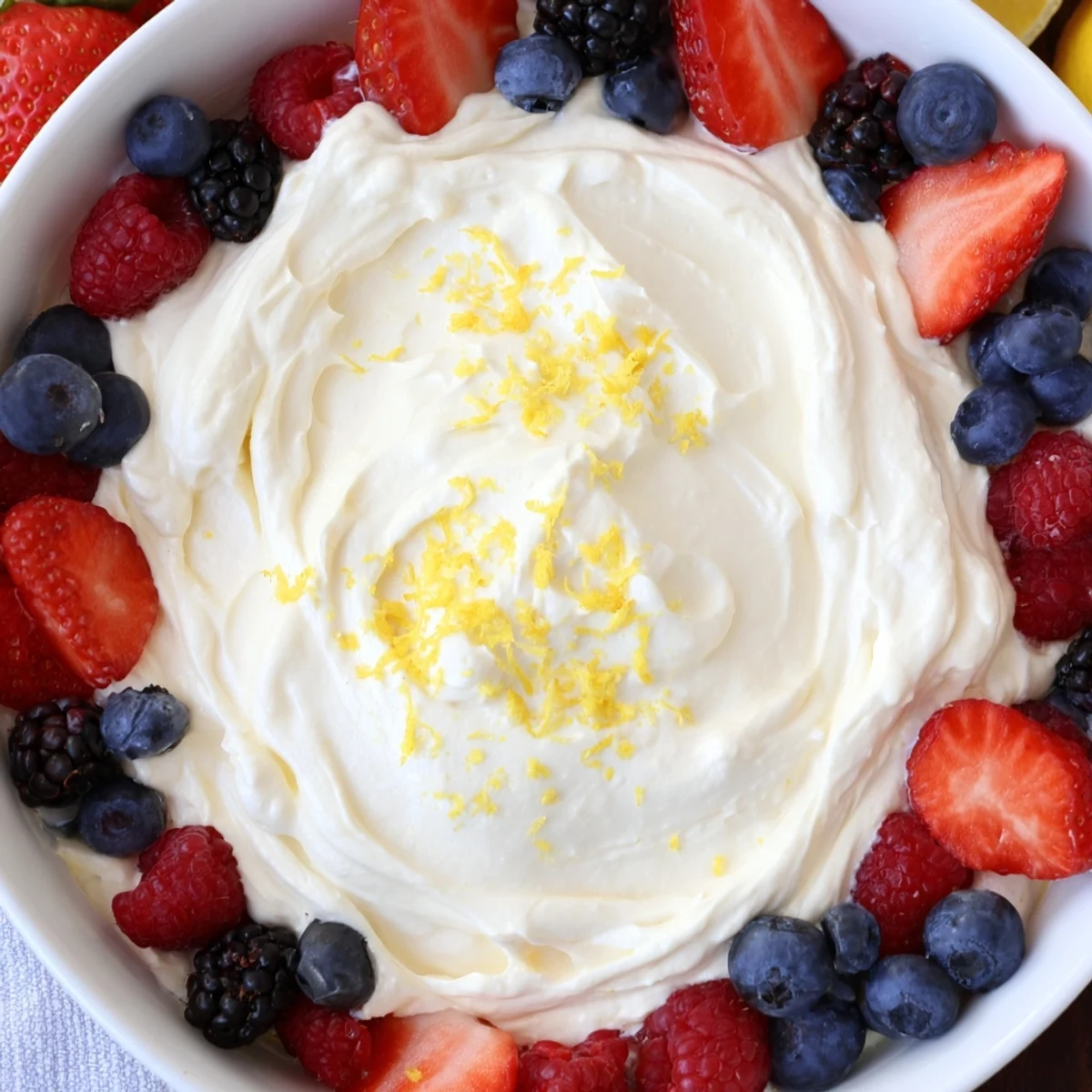 Fluffy cream cheese fruit dip with vibrant berries, a sweet and creamy treat.