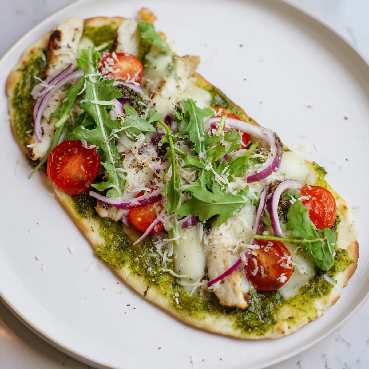 Pesto Chicken Flatbread with melty mozzarella, tomatoes, and red onion, Italian flavors.