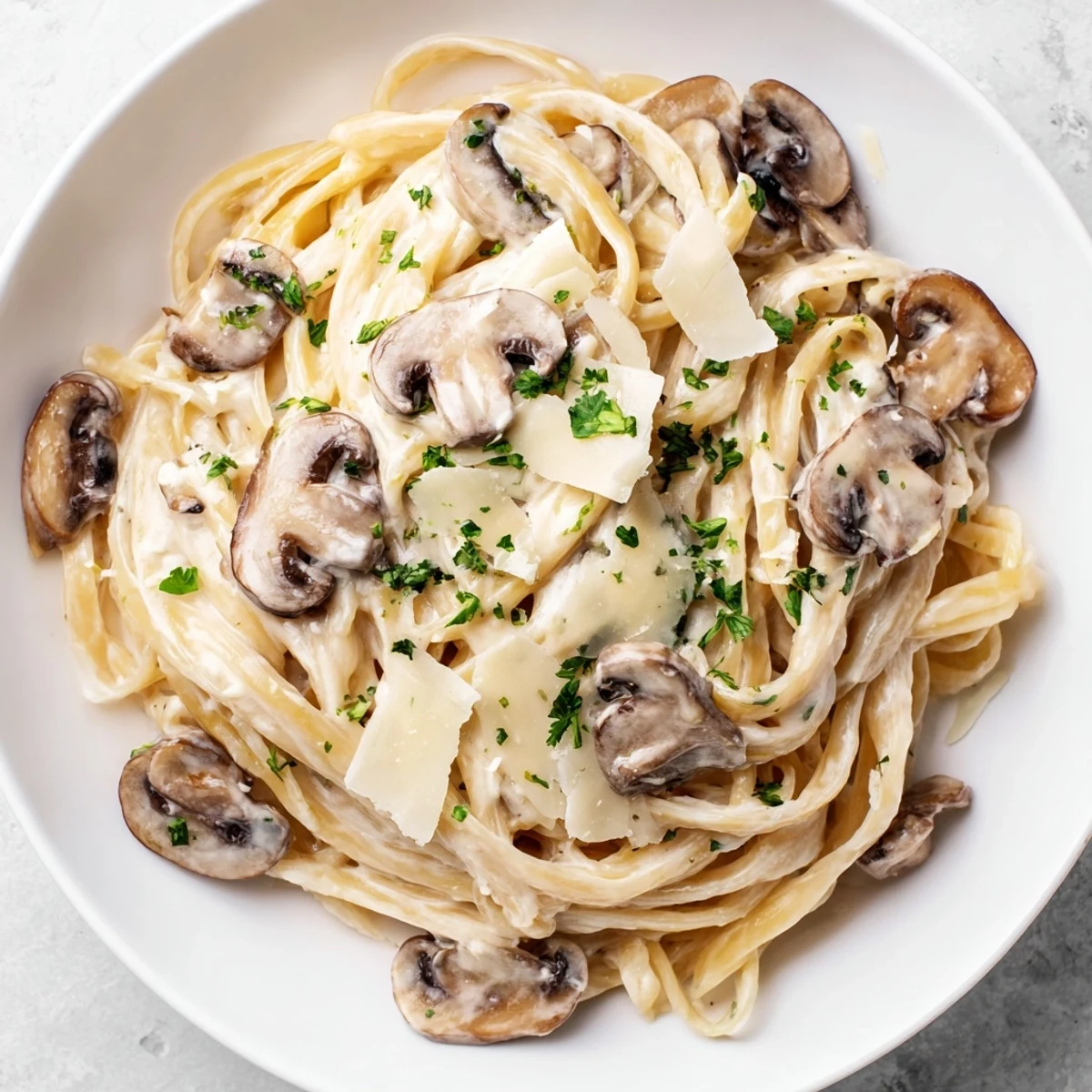 Tongs tossing fettuccine through Creamy Mushroom Alfredo, with steam rising and garlic aroma.