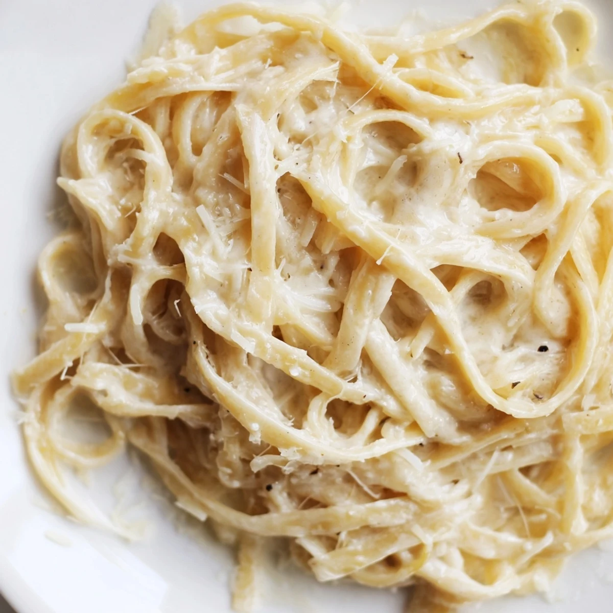 Ein Topf mit Al dente-Nudeln in einer cremigen Sauce aus geröstetem Knoblauch, garniert mit Parmesan und Petersilie.