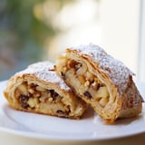 A close-up of a freshly baked apple strudel, showing layers of puff pastry.