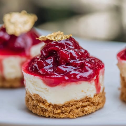 Elegant Kirsch-Rococo mini cheesecakes topped with cherry compote, ready for a dessert plate.
