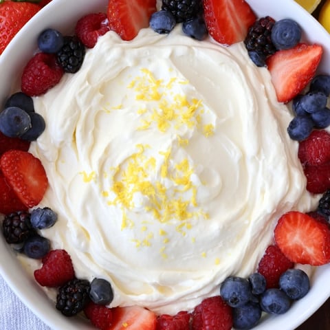 Fluffy cream cheese fruit dip with vibrant berries, a sweet and creamy treat.