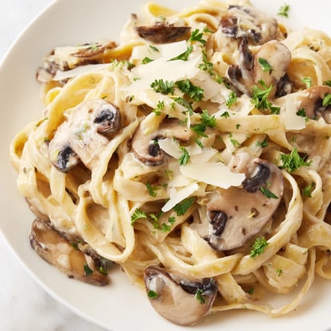 Cremige Mushroom Alfredo pasta in a skillet garnished with fresh parsley, ready to serve.