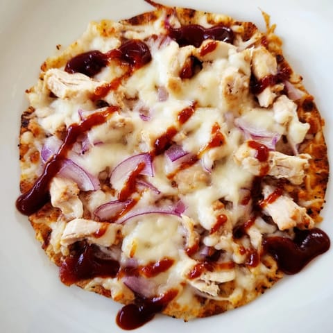 BBQ Chicken Flatbread with drizzled sauce and fresh cilantro, served hot on a rustic wooden board.