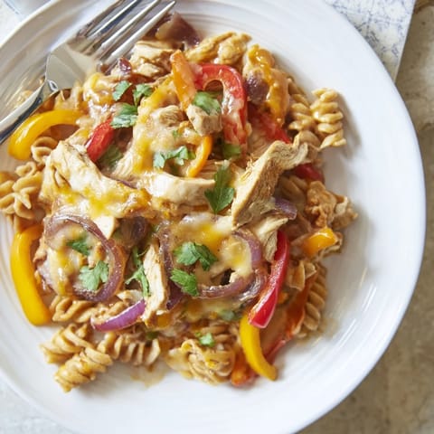 Das Chicken Fajita Pasta Skillet leuchtet in den Farben Mexikos, garniert mit frischem Koriander und Limone.